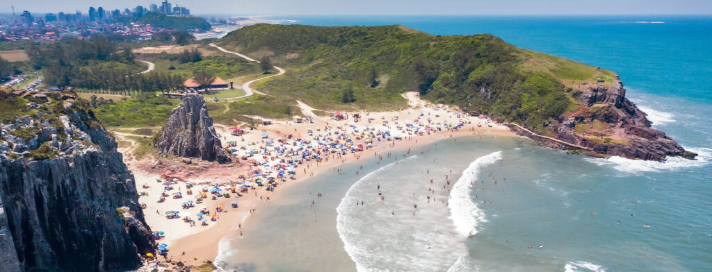 Pessoas na areia da Praia da Guarita, em Torres, no Rio Grande do Sul.